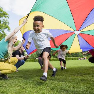 Preschool Aged boy running under a parachute