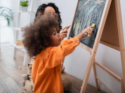 child writing on chalkboard 