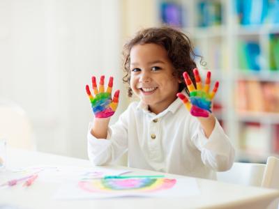 child smiling with paint on hands