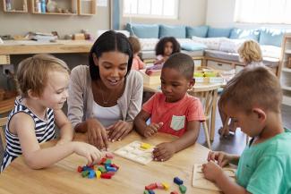 teacher playing with students in preschool classroom