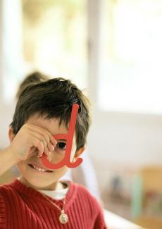 child playing and looking through the hole in the letter 'D'